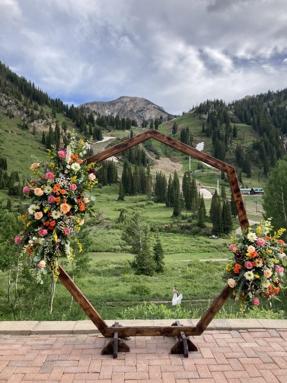 wedding ceremony arch with bright florals, alta ski area in background