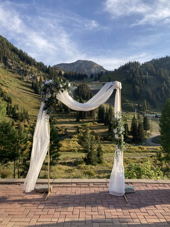 wedding arch with white drapery and green florals, mount baldy and alta ski area in background